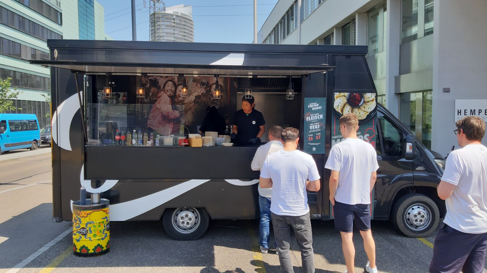 Foodtruck in einem Gewerbegebiet mit wartenden Menschen.